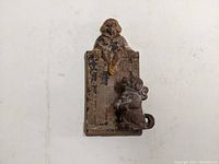 Front view of the antique cast iron door knocker showing the figures of Buster Brown and his dog, original paint visible but worn.