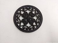 Top view of first cast iron round trivet with floral and scroll cutout design