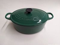 Le Creuset oval Dutch oven with lid, dark green exterior, black knob