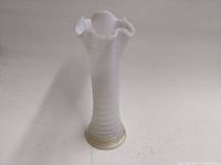 Tall opalescent glass vase with ribbed and swirl pattern, ruffled edge at top, shown from front angle.
