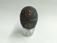 Front view of silver-tone metal egg atop cut glass liner