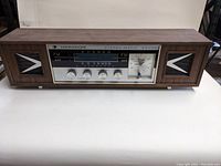 Front view of the Commodore CR-427 radio clock unit showing FM/AM dial, control knobs, and left speaker.