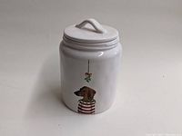 Front view of the white ceramic cookie jar showing dog in striped sweater with mistletoe above.
