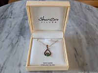 Full view of the Shanore Sterling Silver Claddagh pendant necklace in an open Shanore Silver branded presentation box on a marble surface.