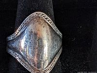 Close-up photo of a sterling silver ring with a domed center and beaded edge on a black display.