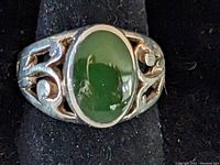 Front view of sterling silver ring with oval green jade stone and scroll openwork band.