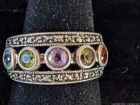 Front view of the sterling silver ring showing five multi-colored stones and marcasite accents on a black stand.