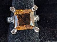 Close-up front view of sterling silver ring with large square amber colored stone