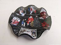 Curved scalloped-edge smokey glass candy bowl showing Christmas themed illustrations and holiday symbols.