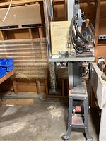Full view of band saw on cast metal stand with manual and accessories on table.