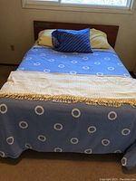 Double size bed made with blue circular-pattern bedding and wooden headboard