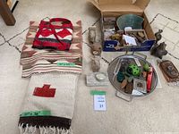 Overview of lot content showing textiles laid flat and an assortment of artifacts and decorations including trays and small boxes