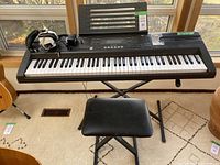Full view of Casio keyboard on X-style stand, with black cushioned stool and wired headphones resting on keyboard.