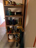 Full view of wooden shelves filled with various vases, pots, decorative items, and figurines including flower-shaped decor and frog figurines.