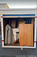 Open POD storage unit packed tightly with various pieces of furniture including sofas, tables, and cushions, showing condition and quantity of stored items.