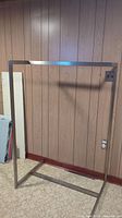 Full view of the metal clothing rack showing its rectangular shape, horizontal hanging bar, and base frame.