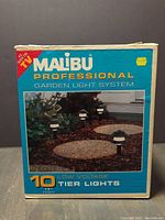 Box of Malibu Professional Garden Light System containing 10 low voltage tier lights, 17 inches high, black and white design