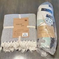 Photo showing new FAB SOFTS 'Throw Jeté' cotton throw with fringe and a wrapped Tofino towel featuring geometric patterns.