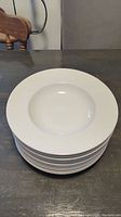 Stack of 11 white porcelain soup bowls, shown from top view