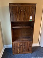Front view of laminate wood cabinet showing upper and lower door compartments and open middle shelf.