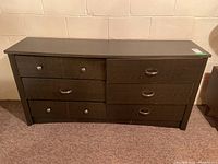 Front view of the dark wood dresser showing six drawers, varying handles and visible wear.