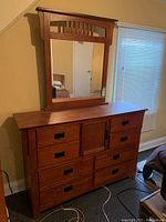 Full view of wood dresser with attached mirror, showing drawer configuration and mirror design