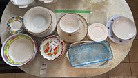 Top view of assorted dinner plates, soup bowls, dessert plates, and blue glass trays arranged on table.