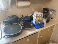 Overview of the lot on kitchen counter including pans, coffee maker, Brita water filter in box, and other cookware.