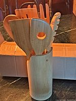 Kitchen utensil set including seven bamboo tools inside bamboo storage container with hanging hole, displayed upright.