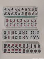 Top view of Mahjong tiles showing characters, dragons, and winds in organized rows.