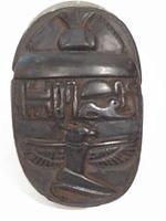 Front view of dark stone carved scarab depicting Egyptian hieroglyphs and symbolic figures.
