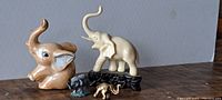 Four elephant figurines displayed on a surface against a neutral background showing the left side view of the lot.