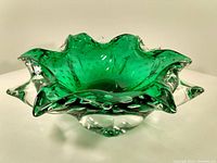 Green glass centerpiece bowl with ruffled edges and clear glass tips, showing side view.