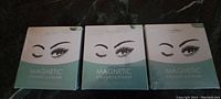 Front of three identical boxes of magnetic eyelashes and eyeliner, showing brand and product type clearly.
