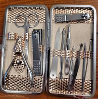 Open metal case showing all included nail care tools held inside the textured interior.