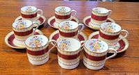 Nine espresso cups and six saucers arranged on wooden surface
