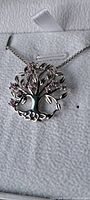 Close-up photo of the silver-tone tree of life pendant showing detailed branches and pink glass stones as leaves.