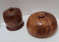Photo of a tall cylindrical wooden container with lid, dark wood with a geometric light line pattern.
