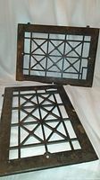 Pair of antique cast iron floor grate covers, rectangular with geometric star and square pattern, showing aged patina and rust.