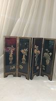 Full view of the four-panel black enamel folding screen with stone inlay flower vases and butterfly designs on the front panels.
