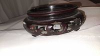 Angled side view of a round Chinese rosewood stand showing carved openwork sides and circular top with recessed center