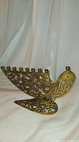 Side angled view showing filigree brass menorah with nine candle holders in bird shape