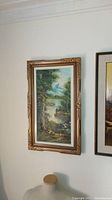 Full view of the framed vintage landscape oil painting on canvas hanging on a wall above a decorative item.