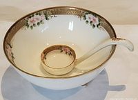 Full view of the interior of footed porcelain mayonnaise bowl with floral hand painted details and matching ladle spoon inside