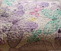 Close-up of quilting and butterfly pattern with pastel colors on quilt surface.
