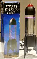 Full view of lava lamp next to its original box, showing the rocket shape and packaging condition