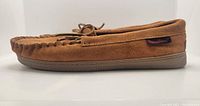 Side profile of light brown suede moccasin slipper with rubber sole and Canyon brand tag