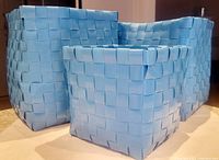 Front and side views of three blue basket weave storage baskets in small, medium, and large sizes arranged together.