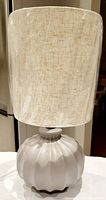 Full view of table lamp showing textured fabric shade and gray ceramic ribbed base