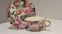Full view of the porcelain tea cup and saucer with rose floral pattern and wavy edges